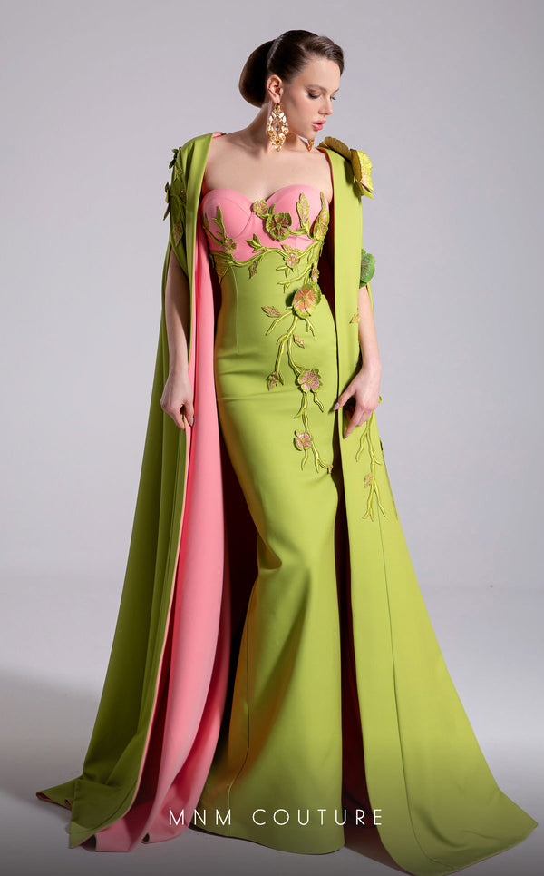 MNM Couture Style F02917 showing a fitted green column gown with a pink strapless bustier top, adorned with embroidered floral appliqués, and paired with a matching green cape. | Couture Shop LA