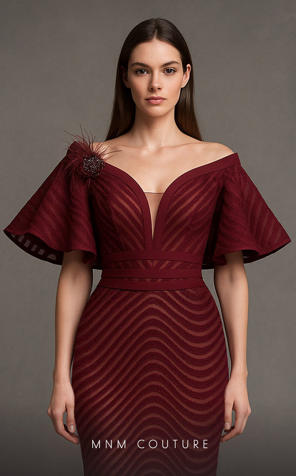 MNM Couture Style F02925 - Elegant black mesh mermaid gown featuring off-shoulder ruffled bell sleeves, a deep V-neckline, and a plumage brooch. | Couture Shop LA