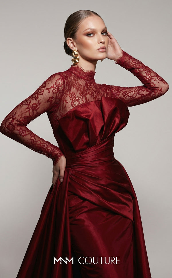 MNM Couture F03006A Chantilly lace and satin column gown featuring a high lace collar, sheer long sleeves, a 3D shoulder bow, an asymmetric ruched waist belt, stomach draping, and an open-front A-line overskirt | Couture Shop LA