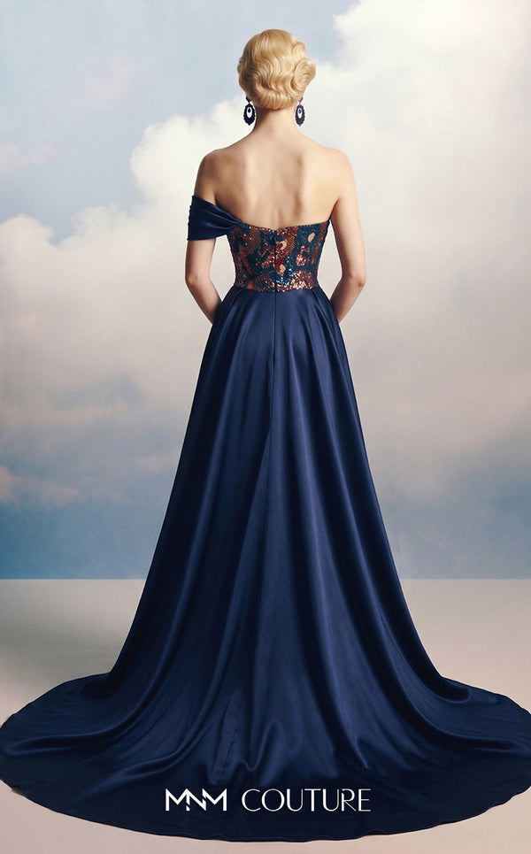 MNM Couture F03044 navy duchess satin gown with diagonal off-shoulder drape, sculptural right-shoulder petal, multicolor sequin-embroidered column, open-front A-line overskirt, and open back | Couture Shop LA.