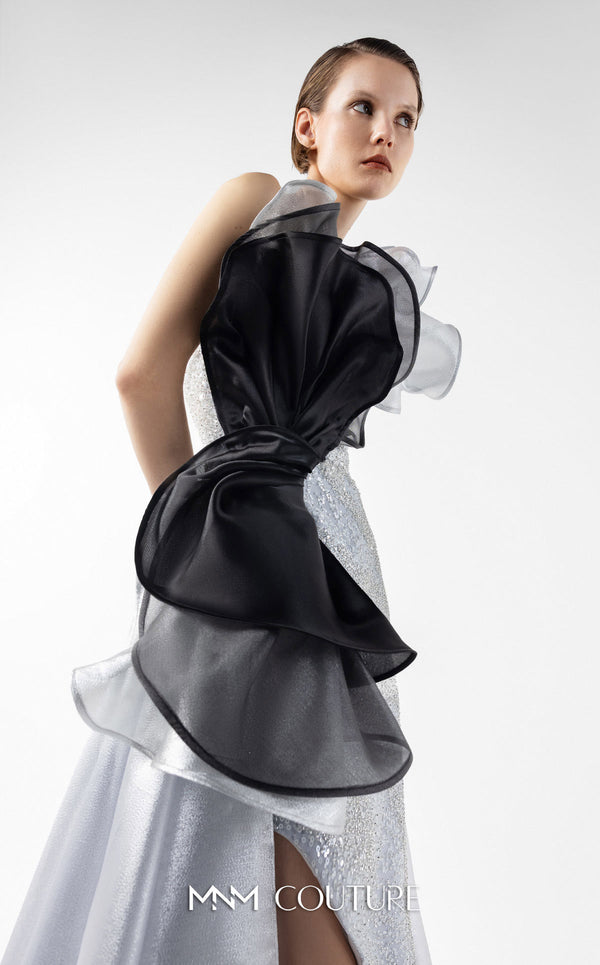 MNM Couture Style G2042 showcasing a silver lace gown with sculptural black and silver lamé organza ruffles, one-shoulder detail, and a high slit. | Couture Shop LA