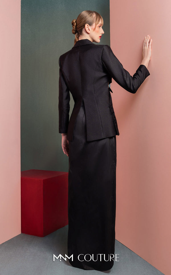 MNM Couture GOF2542 ensemble, with an asymmetrical black mikado piqué blazer featuring side cut-outs and button details, paired with a dramatic high-slit black taffeta skirt. | Couture Shop LA