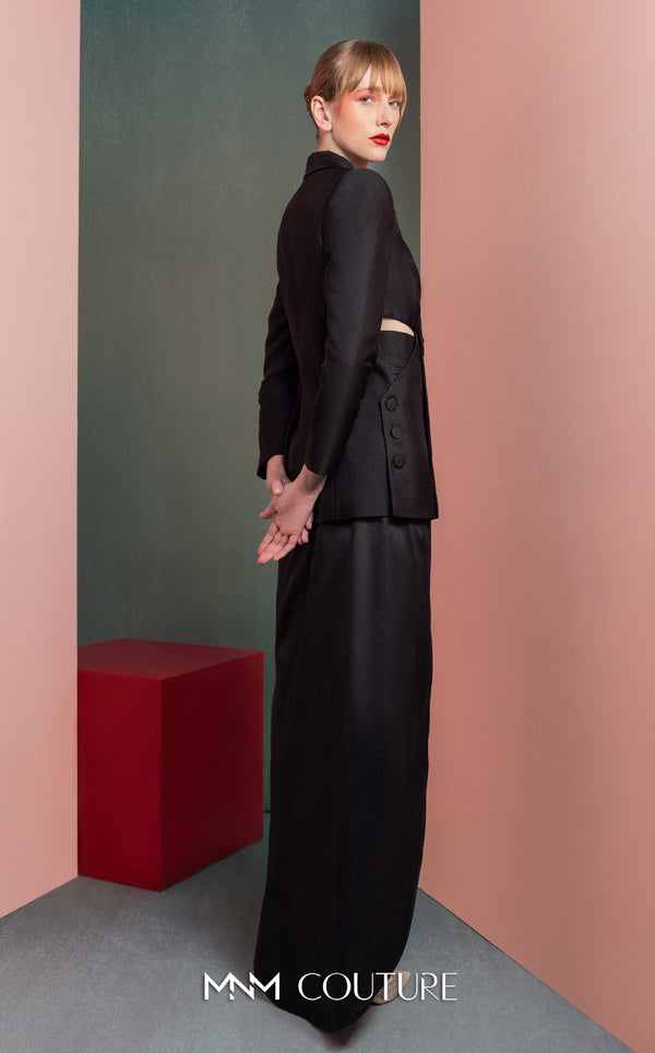 MNM Couture GOF2542 ensemble, with an asymmetrical black mikado piqué blazer featuring side cut-outs and button details, paired with a dramatic high-slit black taffeta skirt. | Couture Shop LA