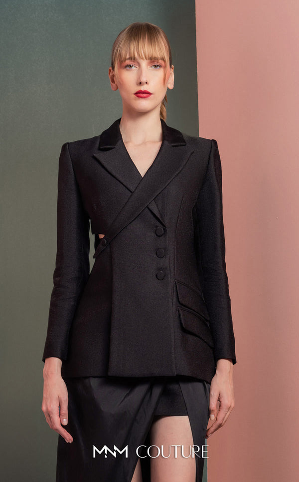MNM Couture GOF2542 ensemble, with an asymmetrical black mikado piqué blazer featuring side cut-outs and button details, paired with a dramatic high-slit black taffeta skirt. | Couture Shop LA