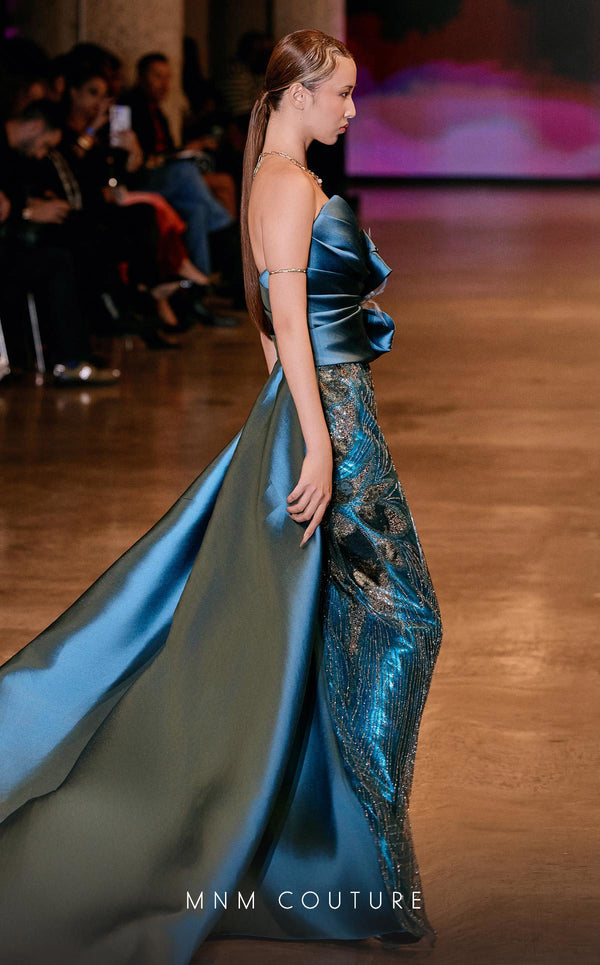 MNM Couture Style J03497 strapless column gown with a beaded skirt, satin train, and asymmetrical deep V-neck. \ Couture Shop LA