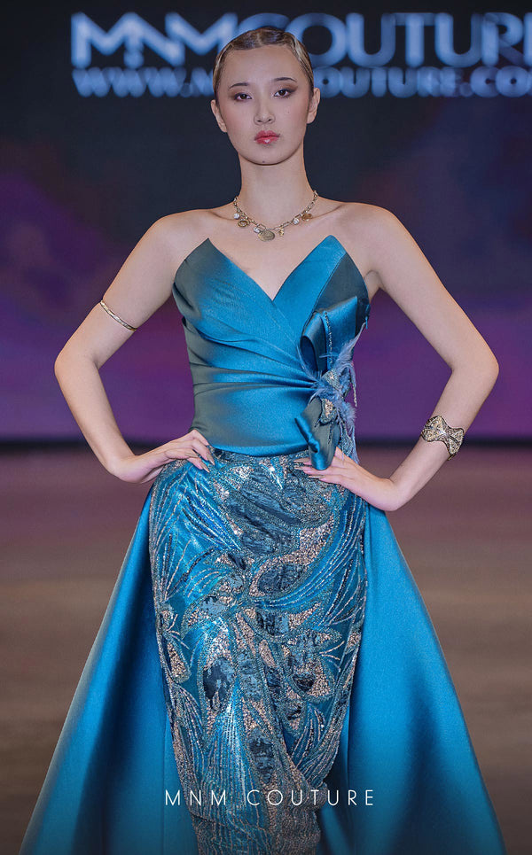 MNM Couture Style J03497 strapless column gown with a beaded skirt, satin train, and asymmetrical deep V-neck. \ Couture Shop LA