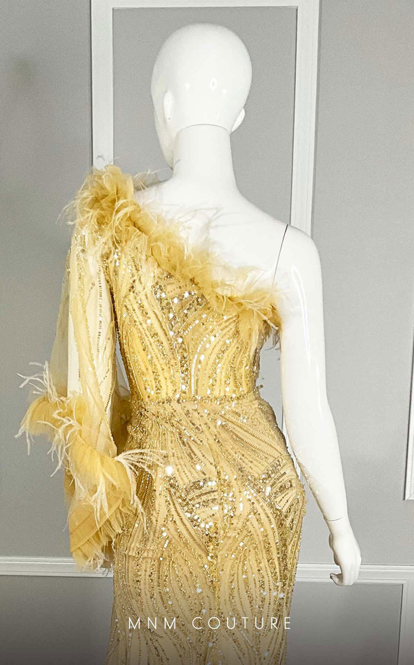 MNM Couture M1073 asymmetric column gown with one long sleeve, sequin and bead embroidery, plumage on the neckline, and a thigh-high slit. | Couture Shop LA