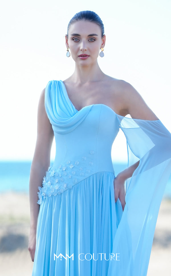 MNM Couture O09003 sky blue one-shoulder Grecian chiffon gown with soft cowl drape, 3D floral cluster at the right hip, densely pleated A-line skirt, and long flowing arm veil | Couture Shop LA