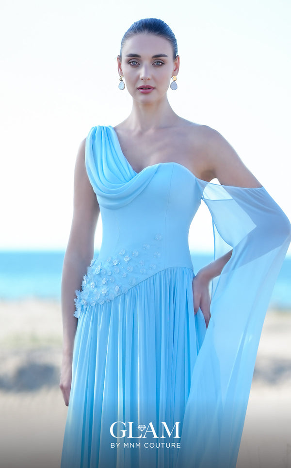 MNM Couture O09003 sky blue one-shoulder Grecian chiffon gown with soft cowl drape, 3D floral cluster at the right hip, densely pleated A-line skirt, and long flowing arm veil | Couture Shop LA