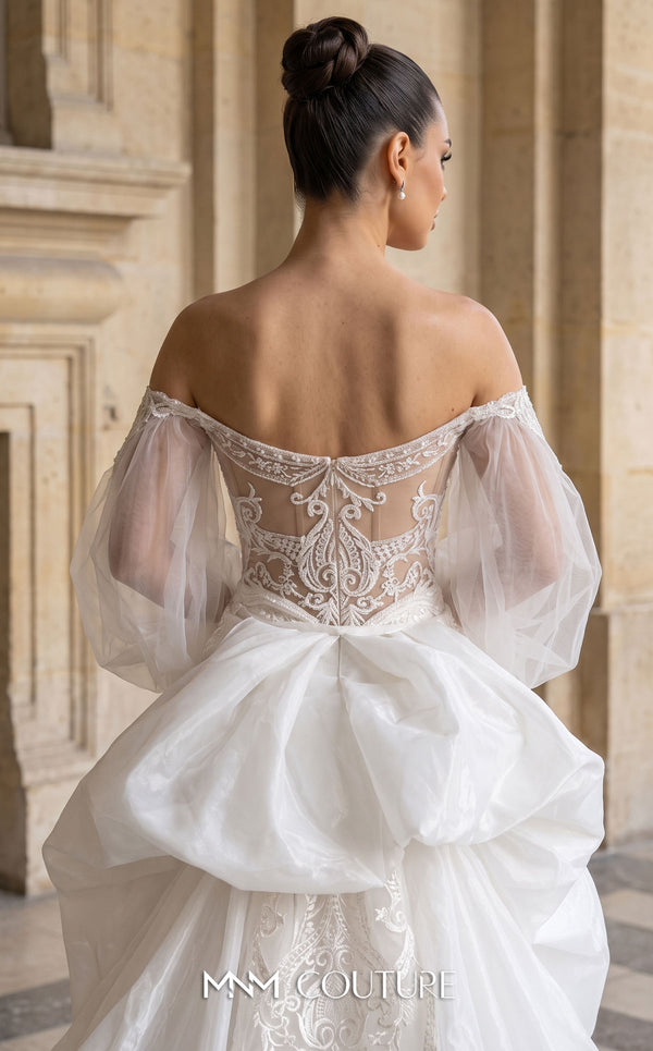 MNM Couture W2301 white off-shoulder sweetheart mermaid wedding dress with heavy 3D floral lace, sheer bishop puff sleeves, open embellished back, oversized structural bow, and layered tulle overskirt with cathedral train | Couture Shop LA