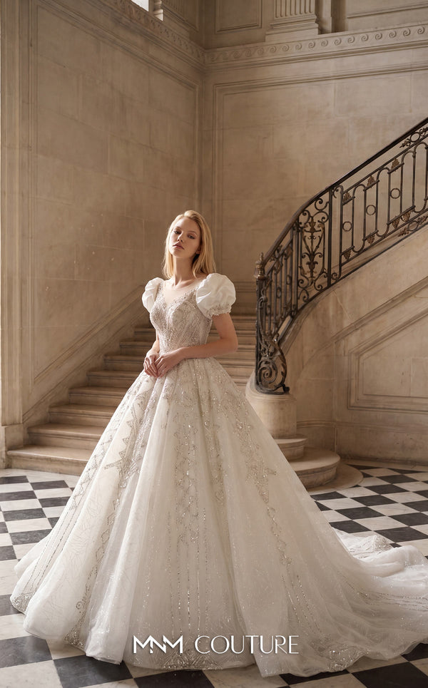MNM Couture W2312 white sweetheart ball gown wedding dress with short structured puff sleeves, diagonal swirling crystal-beaded bodice with center medallion, low open corset back, and voluminous tulle skirt with swirling lace appliqués and cathedral train | Couture Shop LA