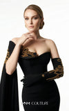 MNM Couture 2606A black stretch crepe off-shoulder mermaid gown with sweetheart neckline, left sheer illusion glove sleeve in gold metallic floral lace, right floor-length crepe cape drape with gold lace, open upper back, and sweep train | Couture Shop LA
