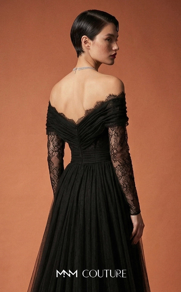 MNM Couture Style B1141 featuring a flared black organza gown with an off-the-shoulder sweetheart neckline, long sleeves, and a long, flowing train cape at the back.| Couture Shop LA.