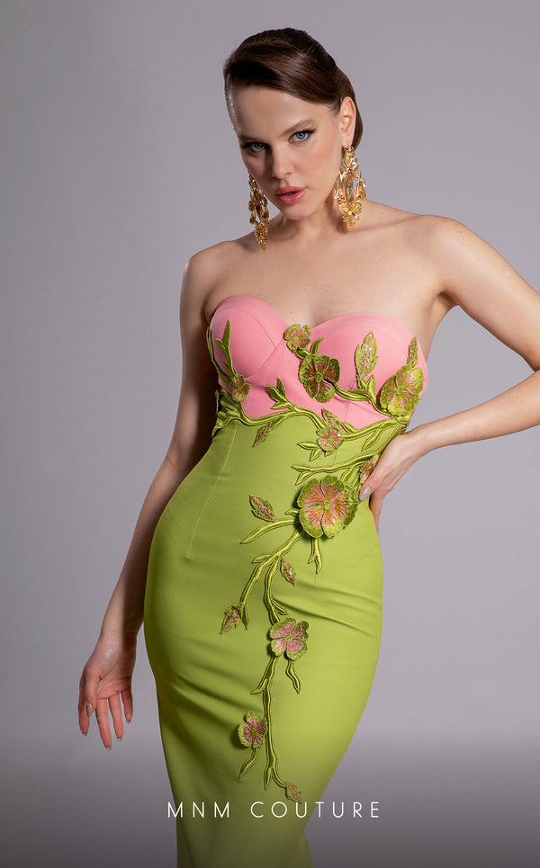 MNM Couture Style F02917 showing a fitted green column gown with a pink strapless bustier top, adorned with embroidered floral appliqués, and paired with a matching green cape. | Couture Shop LA