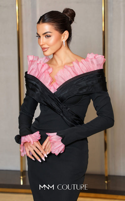 MNM Couture Style F02941 showing a black form-fitting evening gown with a pink off-the-shoulder ruffle detail, matching ruffled cuffs on the long sleeves, and a high back slit. | Couture Shop LA