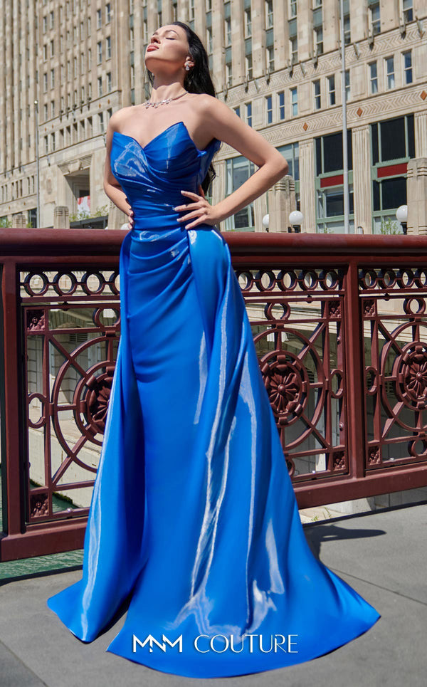 A glamorous MNM Couture G1419 metallic sheath gown featuring a strapless pleated bodice, faux-wrap design, pointed neckline, and a dramatic overskirt. | Couture Shop LA