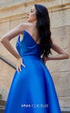 A glamorous MNM Couture G1419 metallic sheath gown featuring a strapless pleated bodice, faux-wrap design, pointed neckline, and a dramatic overskirt. | Couture Shop LA
