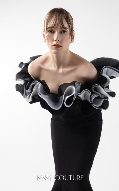 MNM Couture Style G2036 showcasing a black off-shoulder mermaid gown with long sleeves and voluminous, sculptural organza ruffles in silver, off-white, and anthracite. | Couture Shop LA