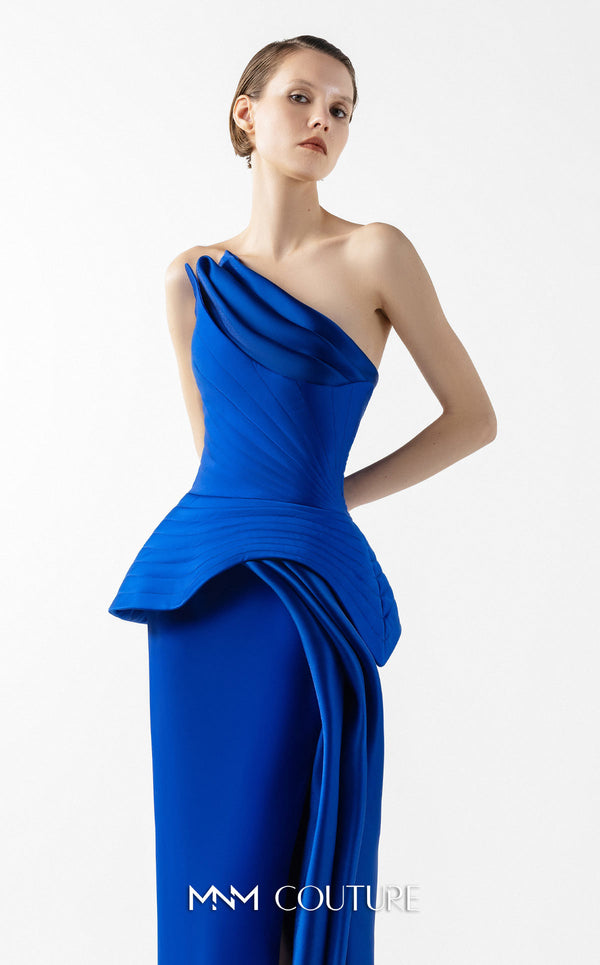 MNM Couture Style G2044 showcasing a royal blue one-shoulder crepe gown with a structured peplum, folded organza drapes, a high slit, and a side train. | Couture Shop LA