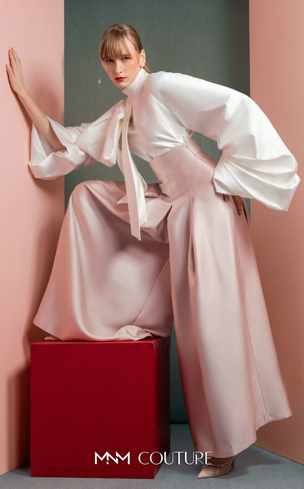 MNM Couture GOF2523 two-piece ensemble, featuring a white taffeta blouse with dramatically oversized sleeves and a front knot, paired with pink taffeta high-waisted, wide-leg pants. | Couture Shop LA