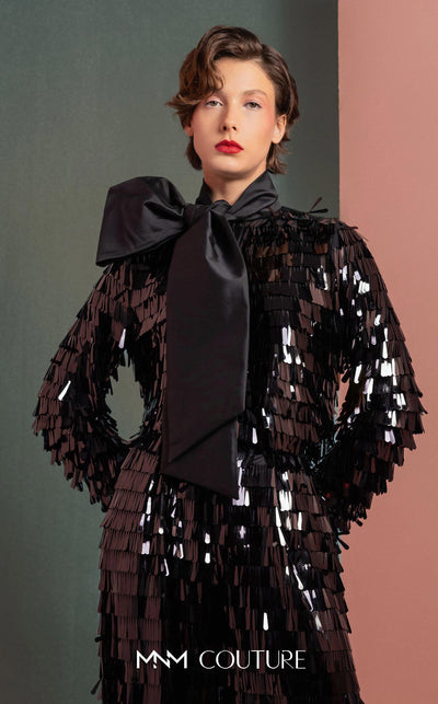 MNM Couture GOF2526 two-piece black sequin ensemble, featuring a long-sleeve blouse with a large taffeta bow at the neck and matching flared sequin pants. | Couture Shop LA
