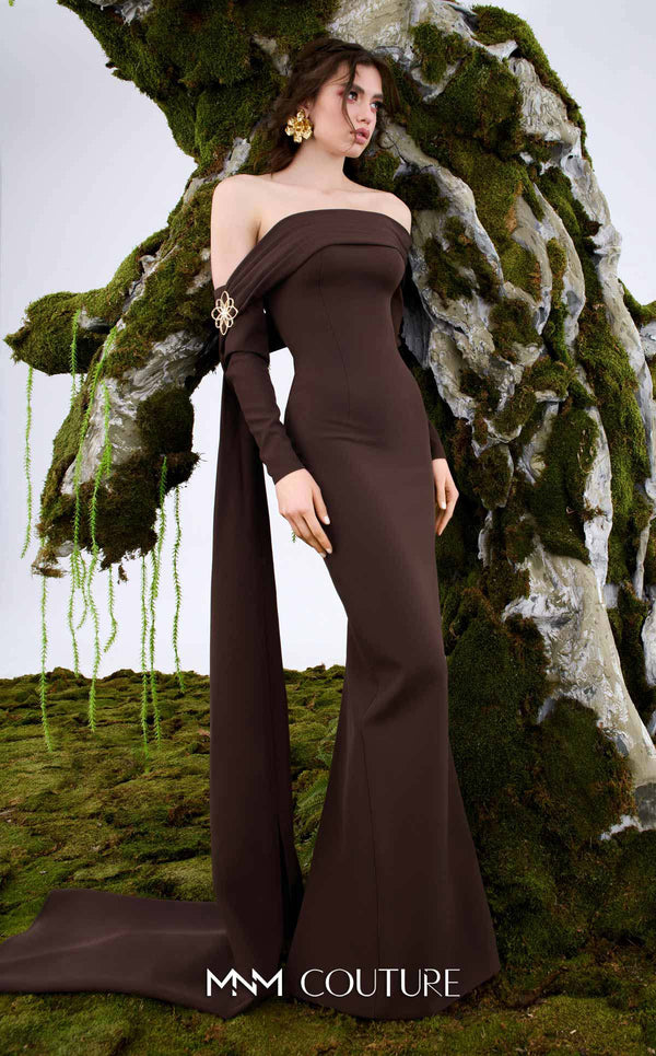 MNM Couture Style N0674 showcasing a brown fitted column gown with straight-across pleated neckline, long sleeves, asymmetrical design, flower brooch, and flowing train | Couture Shop LA