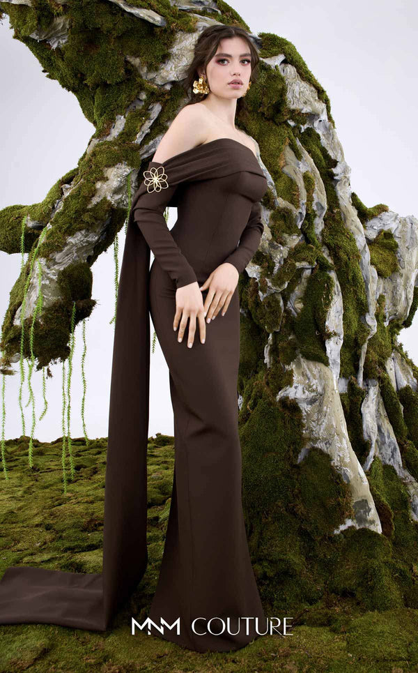 MNM Couture Style N0674 showcasing a brown fitted column gown with straight-across pleated neckline, long sleeves, asymmetrical design, flower brooch, and flowing train | Couture Shop LA