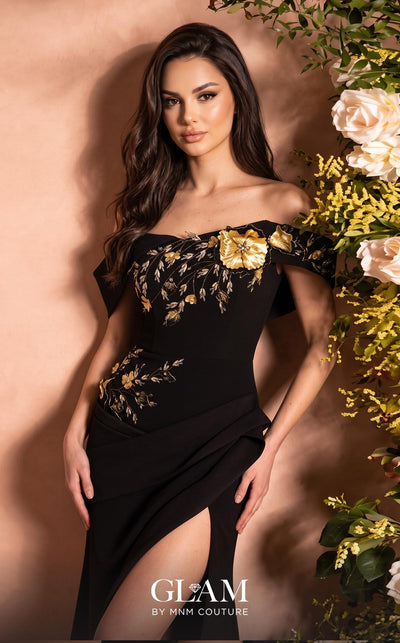 MNM Couture O07832 black stretch crepe off-shoulder column gown with folded bandeau neckline, cap bands, 3D floral and metallic botanical appliqué cascade from left bust to right hip, asymmetric draped overskirt, and high left leg slit | Couture Shop LA
