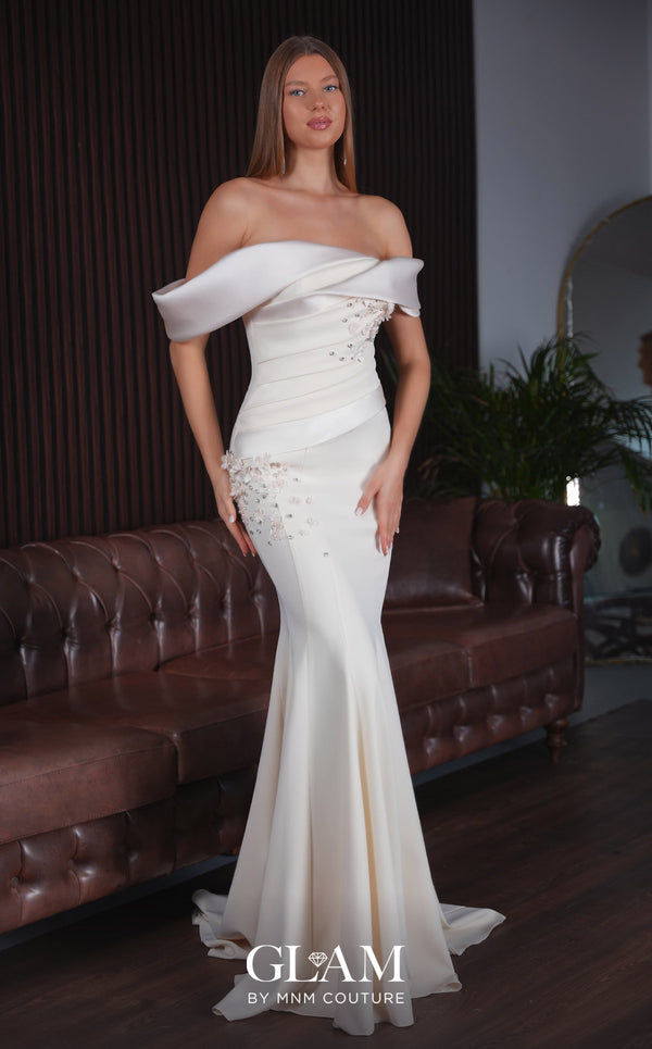 MNM Couture O07835 black stretch crepe mermaid gown with high folded satin drape at left shoulder, diagonal neckline, satin cap down right arm, wide satin waistband, asymmetric left hip satin panel, 3D floral appliqués with crystals and pearls, open back, and sweep train | Couture Shop LA