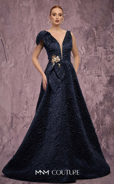MNM Couture Style Q1150 navy blue brocade ballgown with deep V-neckline, mesh inset, bow detail, and gold and crystal floral embellishments at waist and shoulder. | Couture Shop LA