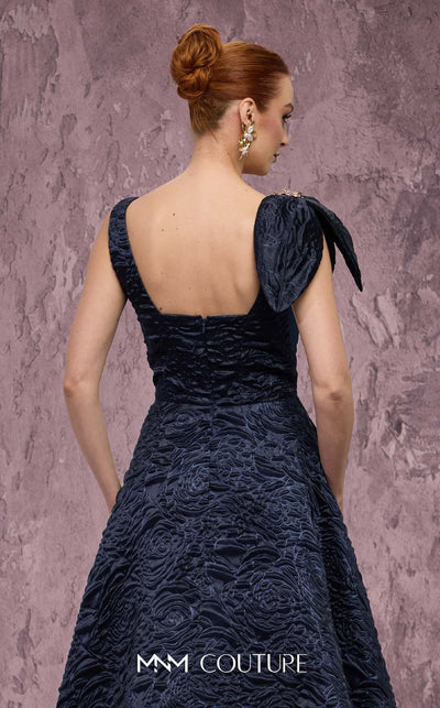 MNM Couture Style Q1150 navy blue brocade ballgown with deep V-neckline, mesh inset, bow detail, and gold and crystal floral embellishments at waist and shoulder. | Couture Shop LA