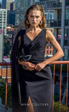 MNM Couture V07523 black column gown with rayon crepe, cape sleeve, and rhinestone brooch accents.| Couture Shop LA