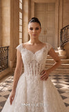 MNM Couture W2314 white off-shoulder ball gown wedding dress with structured flat shoulder drapes, pearl-beaded lace sweetheart bodice, 3D floral appliqués massed at the hem, corset lace-up back, and separate back overskirt with cathedral train | Couture Shop LA